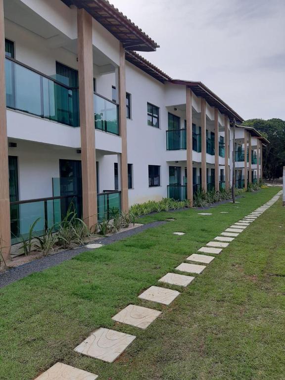 a building with a grass yard in front of it at Ilhéus North Residence Danilo in Uruçuca