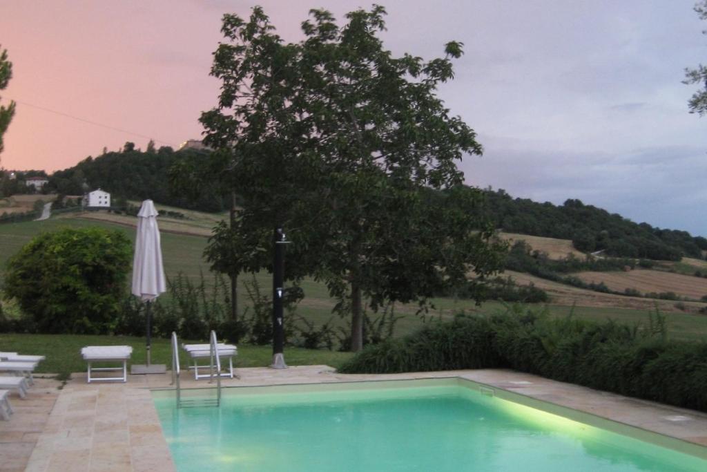 a swimming pool with chairs and an umbrella at Villa Bella Rosa in Fratte Rosa