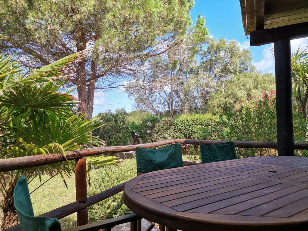une table et des chaises en bois sur une terrasse avec des arbres dans l'établissement Villetta Trilocale con Giardino 1.3, à Porto Pollo