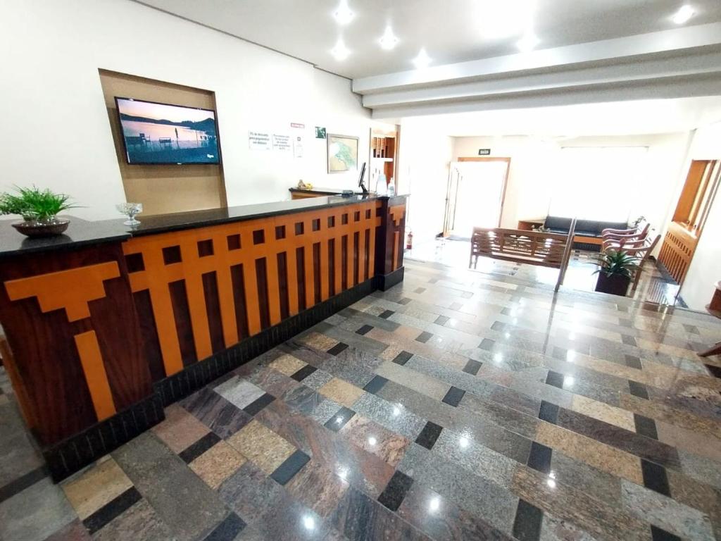 a lobby with a reception desk and a living room at Hotel Cidade in Passos