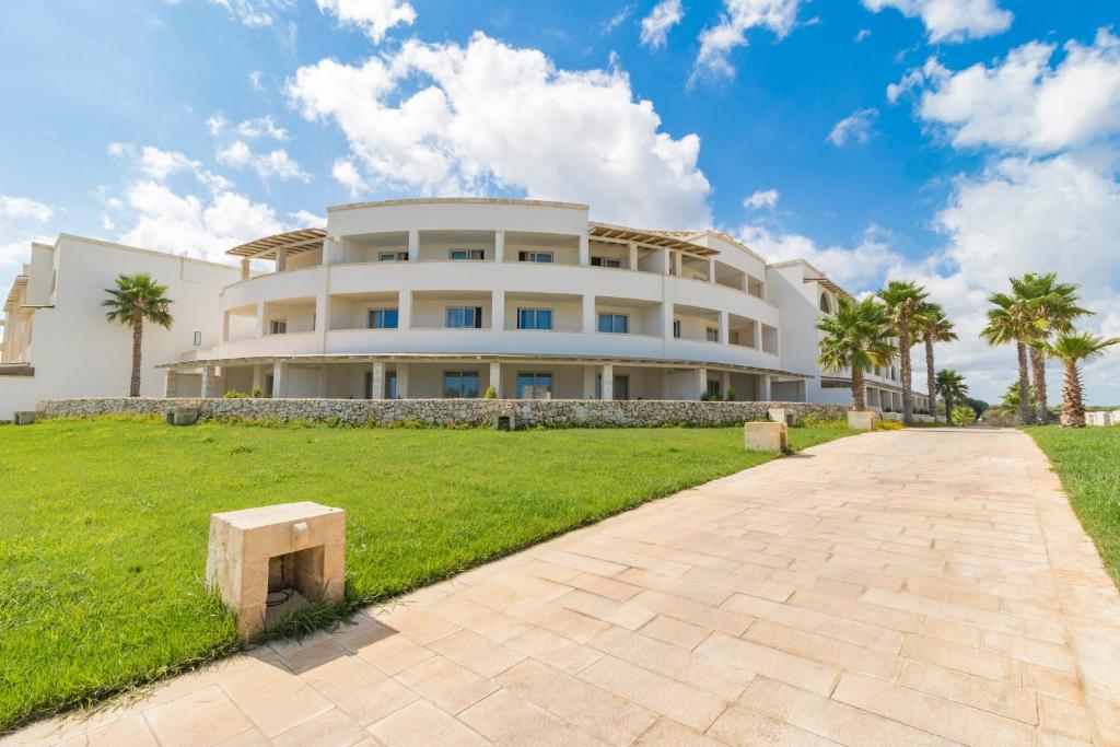 a large white building with palm trees in front of it at HOTEL BARONE DI MARE in Torre dell'Orso