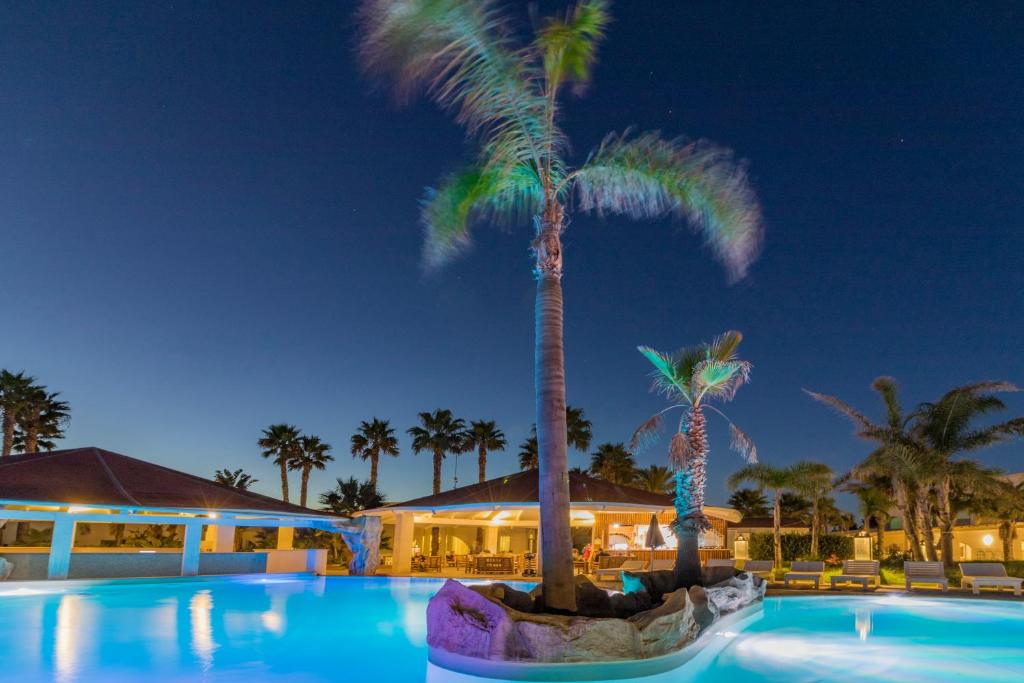 a swimming pool with palm trees in a resort at HOTEL BARONE DI MARE in Torre dell'Orso