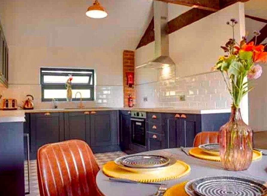 uma cozinha com armários azuis e uma mesa com cadeiras em Hayes Suite em Oswestry