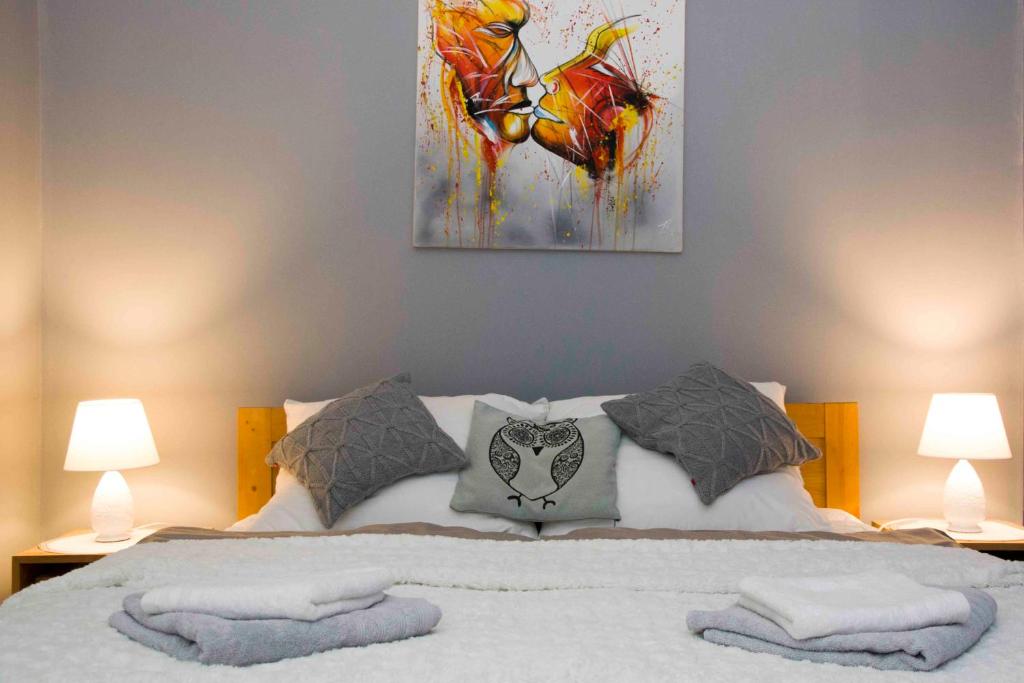 uma cama com duas almofadas e um quadro na parede em Apartament Grapa em Żywiec