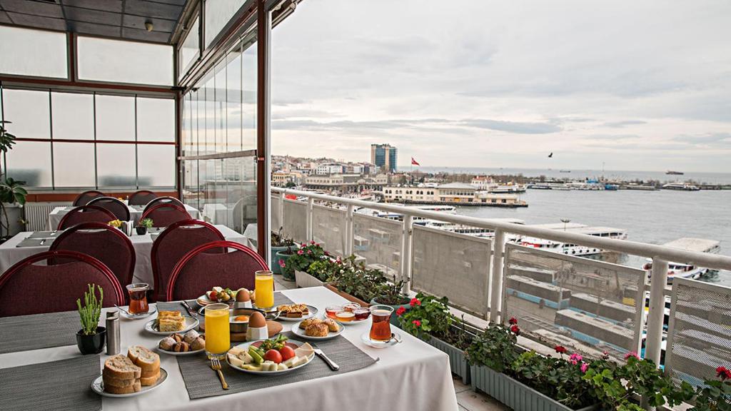 einen Tisch mit Speisen auf einem Balkon mit Blick auf das Wasser in der Unterkunft Kadıköy Rıhtım Hotel in Istanbul