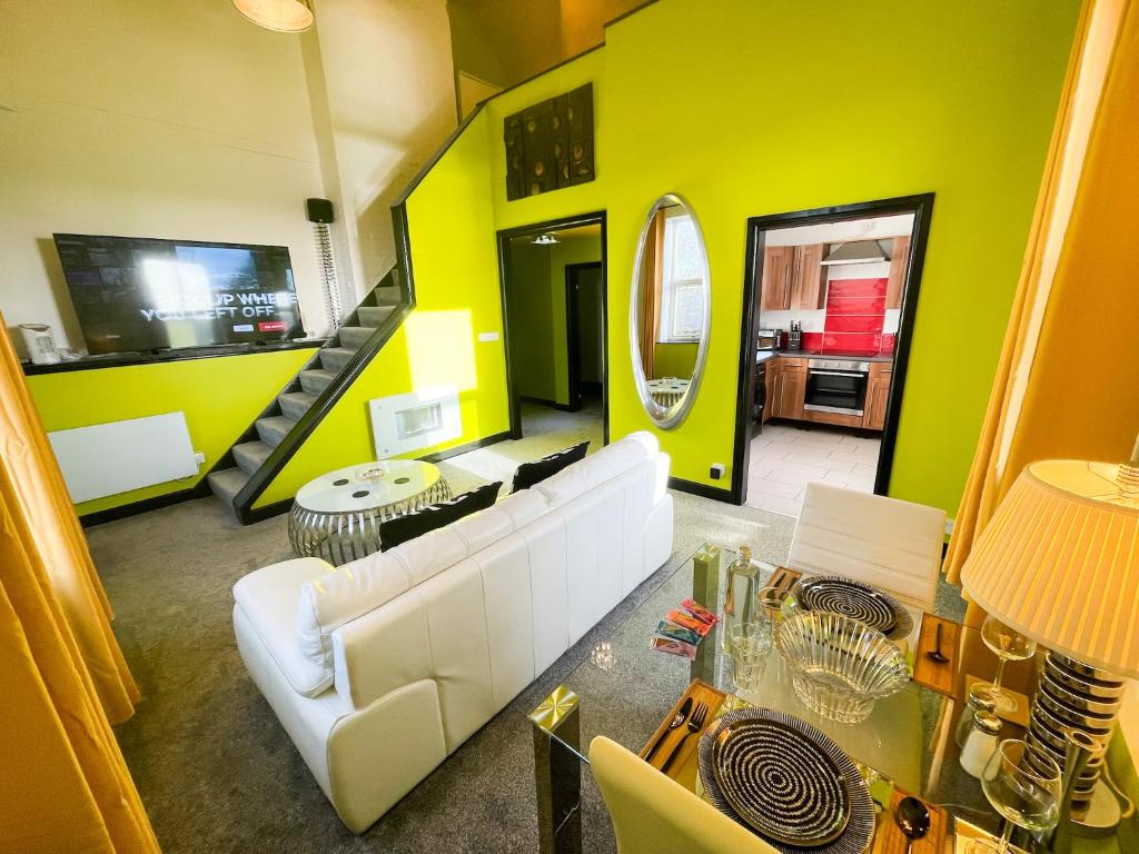 a living room with a white couch and a yellow wall at PHOENIX Executive Apart-Hotel in Goole