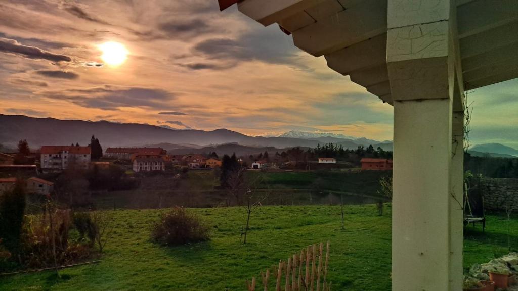 uma vista de um campo com o pôr-do-sol ao fundo em La buganvilla en Udías em Udias