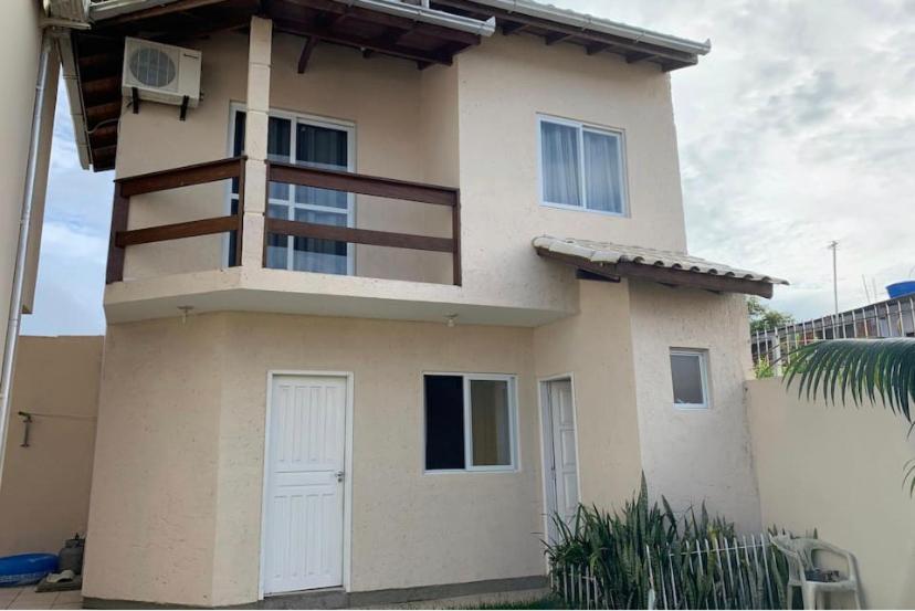 Cette maison dispose d'une porte blanche et d'un balcon. dans l'établissement Casa Aconchegante em rua familiar, à Florianópolis