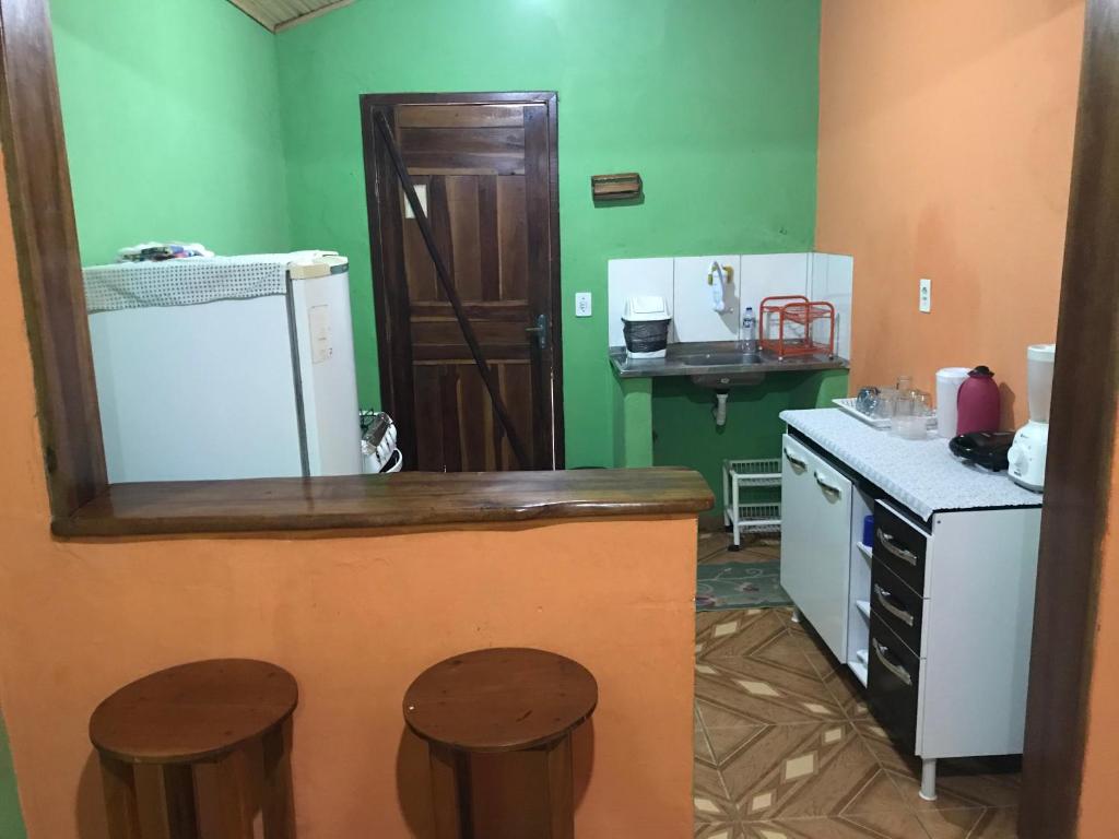 a kitchen with a counter and two stools in it at Casa Laranja in Vale do Capao