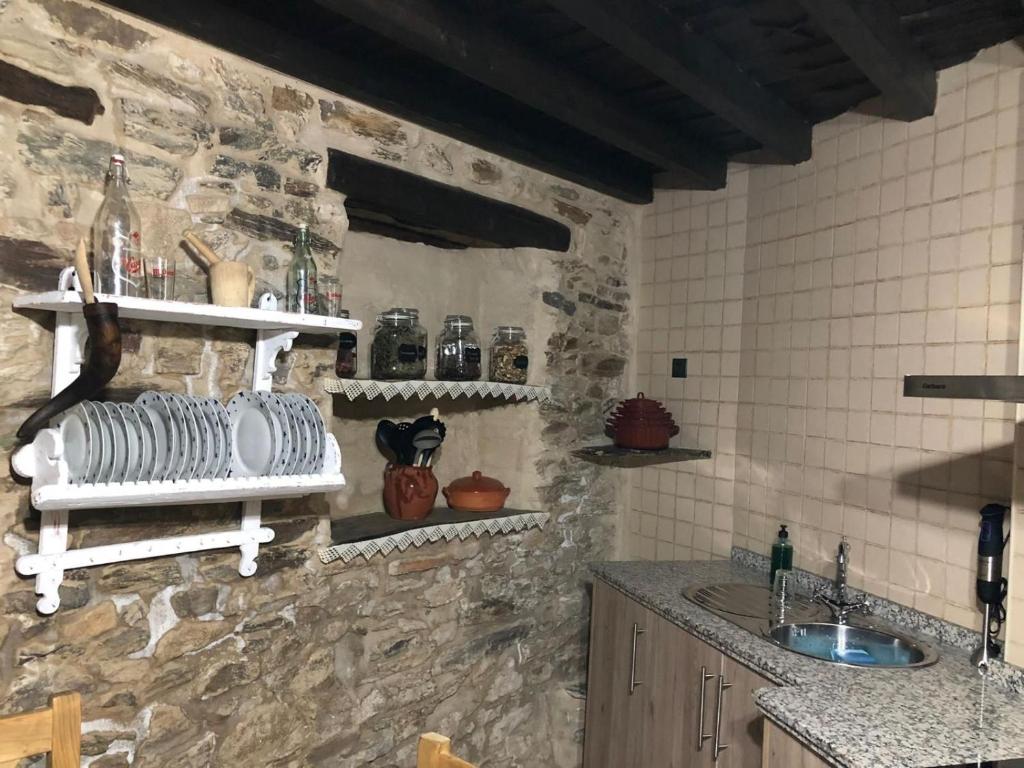 a kitchen with a sink and a stone wall at Casa Rural La Moraquintana in Santibáñez el Bajo