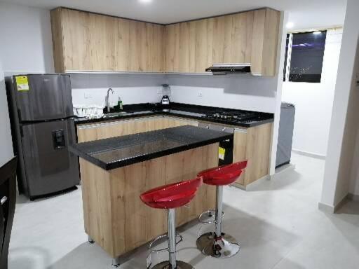 cocina con encimera y 2 taburetes rojos en Hermoso apartamento familiar con parqueadero privado, en San Gil