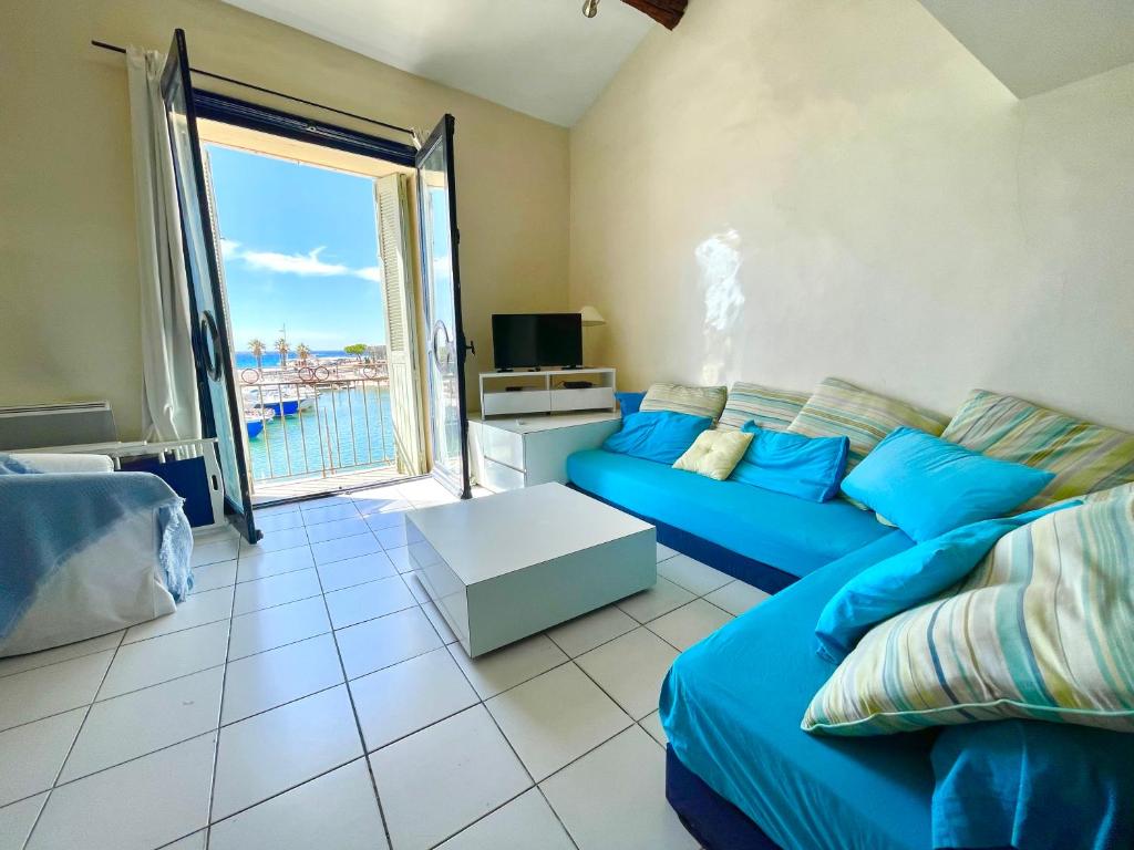 sala de estar con sofá azul y ventana grande en L'AUTHENTIQUE - Sur le Port - Parking - Wifi en Cassis