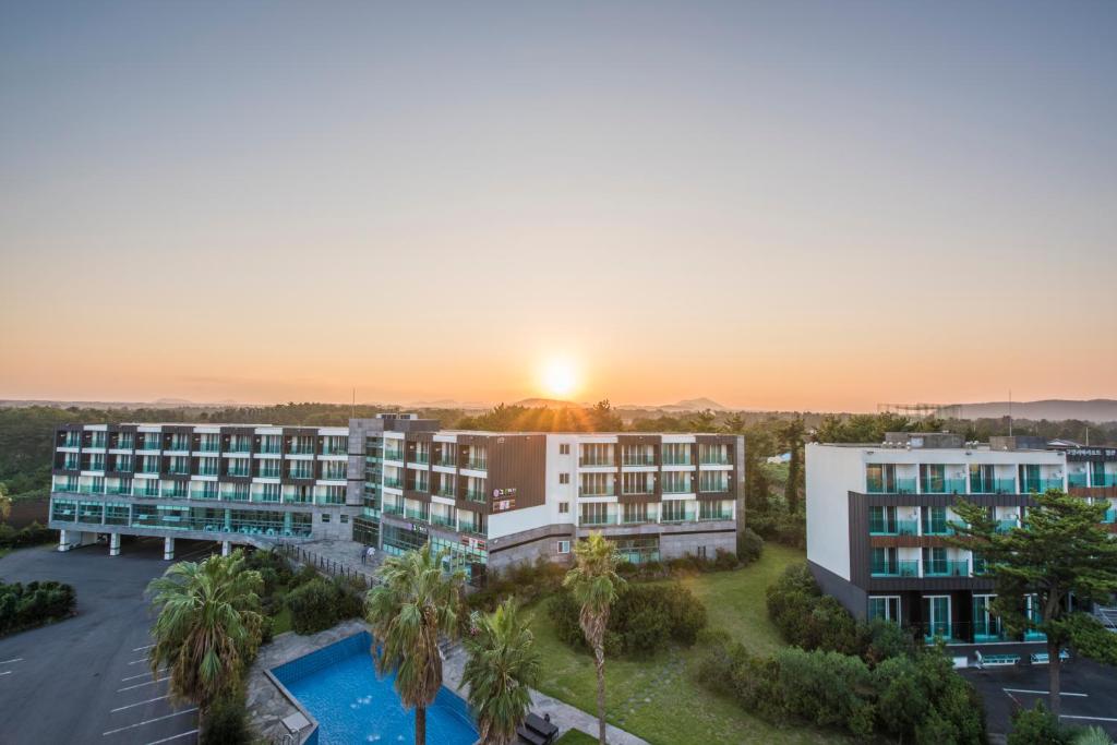 una vista aérea de un hotel con una puesta de sol en el fondo en Cordelia Resort, en Seogwipo