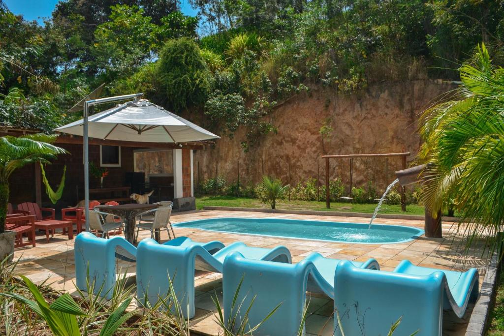 a pool with chairs and a table and an umbrella at Chacara Maluco Beleza 2 in Gravatá