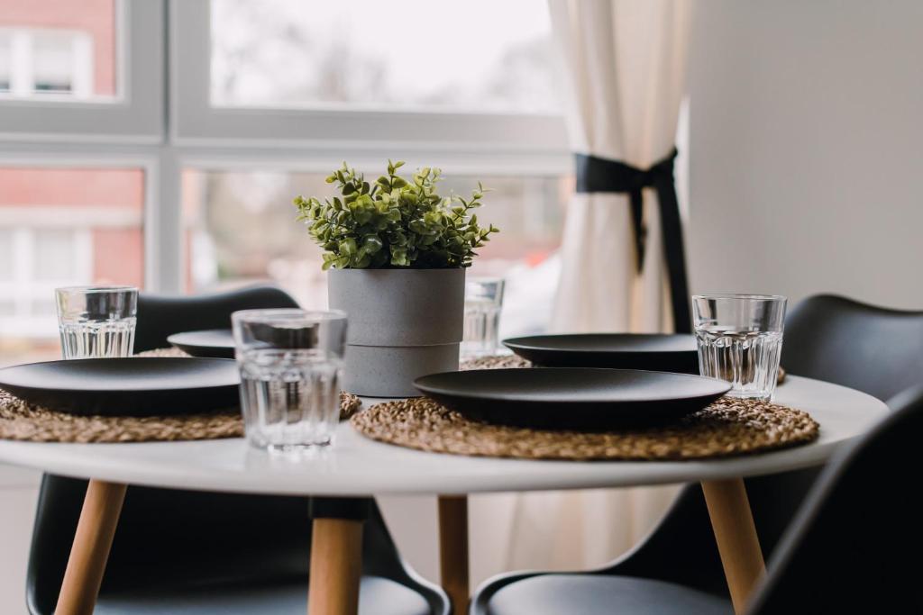 a table with plates and glasses and a plant on it at SuperbSleep Apartments in Glasgow