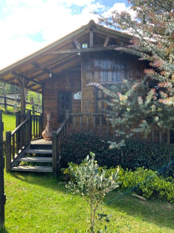 Cabaña de madera con escaleras que conducen a un porche en Acogedora cabaña de madera en la naturaleza para desconectarse, en Sogamoso