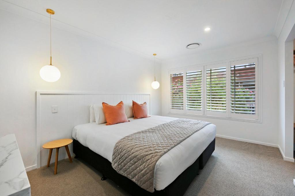 a white bedroom with a large bed with orange pillows at Mediterranean Surfers Paradise Townhouse with BBQ in Gold Coast