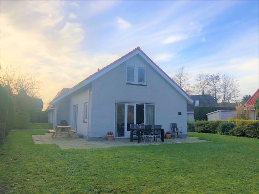 una casa blanca con una mesa y sillas en un patio en Strand Villa Stern Noordwijk, en Noordwijk