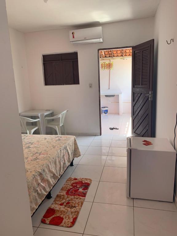 a bedroom with a bed and a table and a door at Chalé Recanto do Paraíso in Galinhos