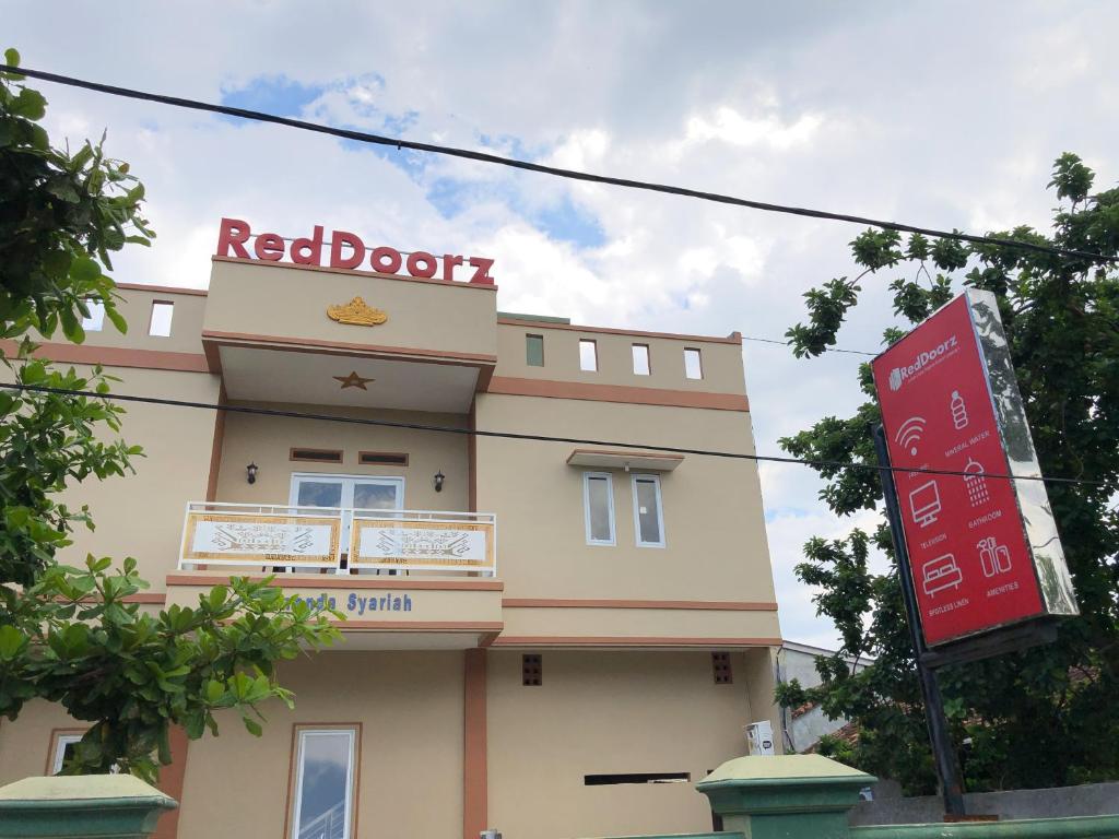 ein rotes Türgebäude mit einem Schild davor in der Unterkunft RedDoorz Syariah at Jalan Pangeran Antasari 4 Lampung in Tanjungkarang