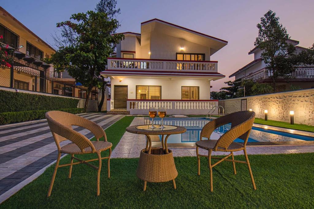 a patio with two chairs and a table in front of a house at StayVista's Brookvale Cottage - Dive into tranquility with pool view and gazebo in Lonavala