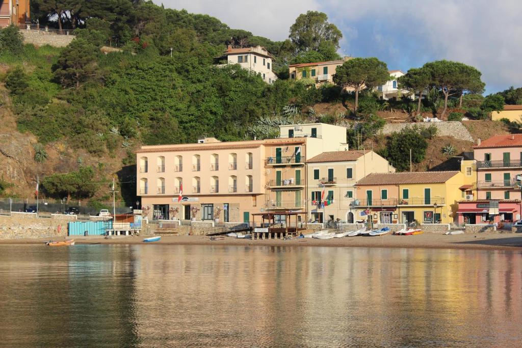 un gruppo di edifici sulla riva di un corpo idrico di Hotel l'Approdo a Porto Azzurro