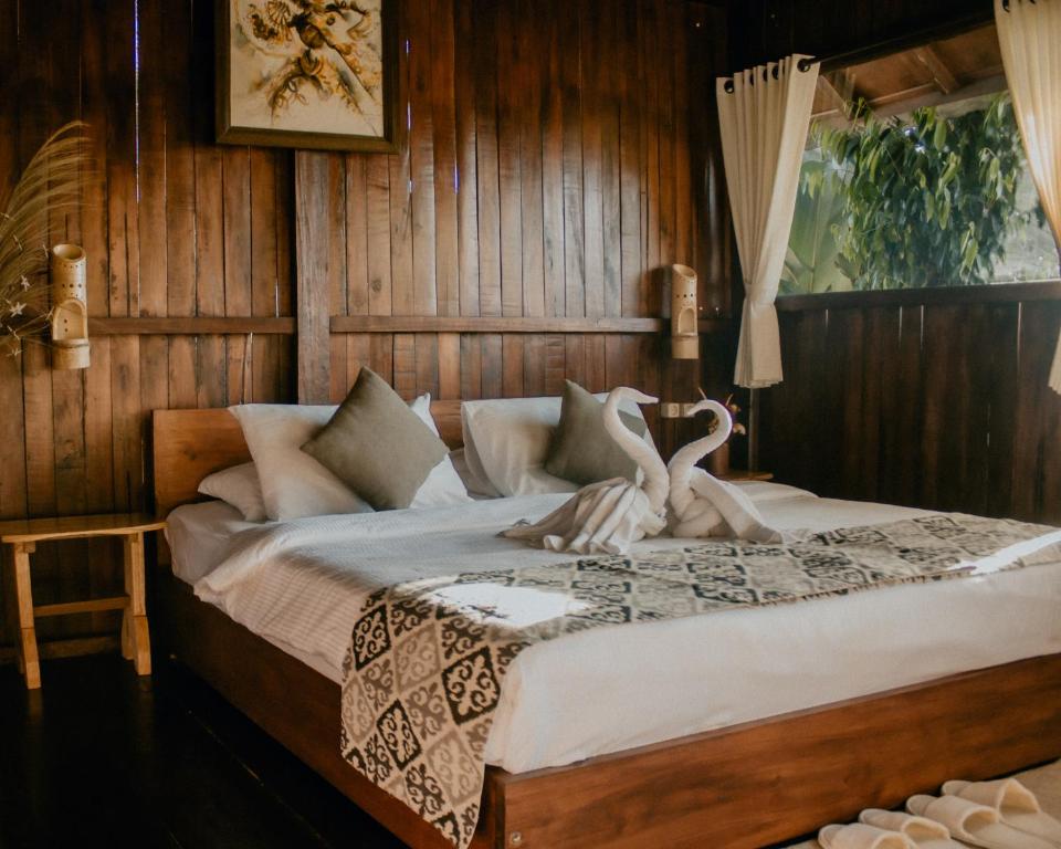 Da'Kayu Bali Homestay في موندوك: غرفة نوم عليها سرير وبجعتين