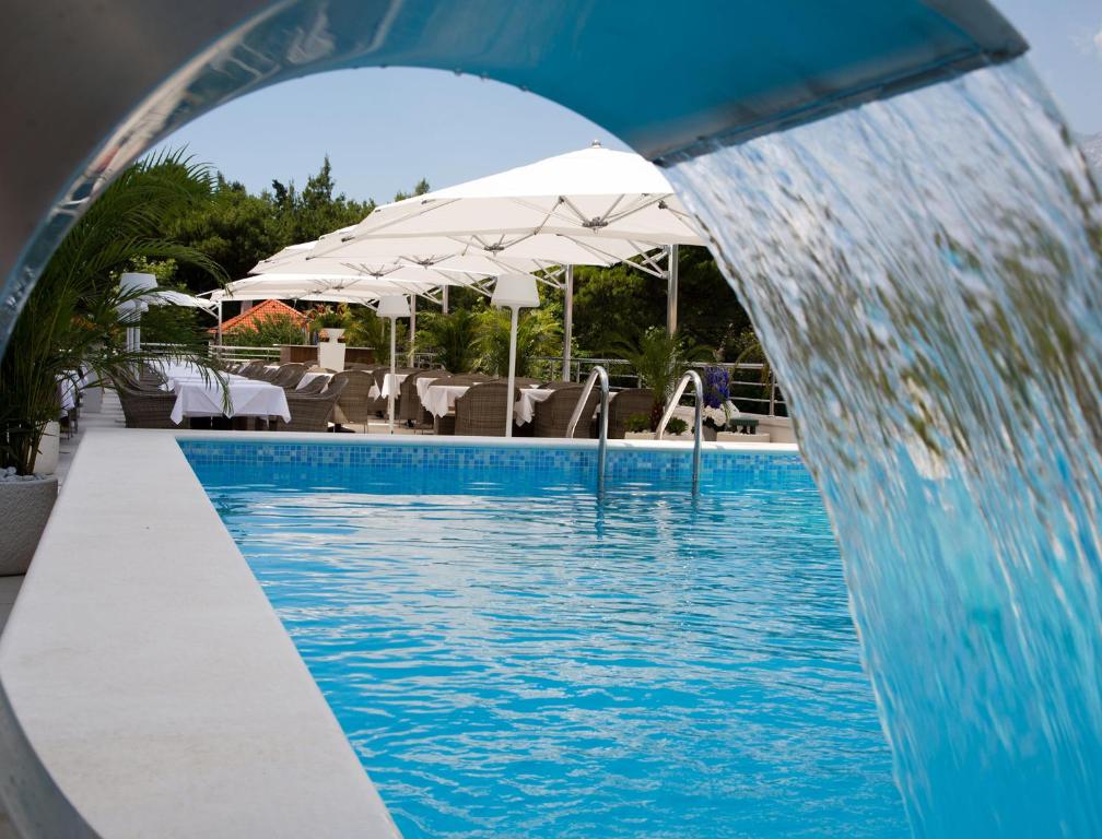 a swimming pool with a water fountain in front of it at Aparthotel Miramare in Makarska