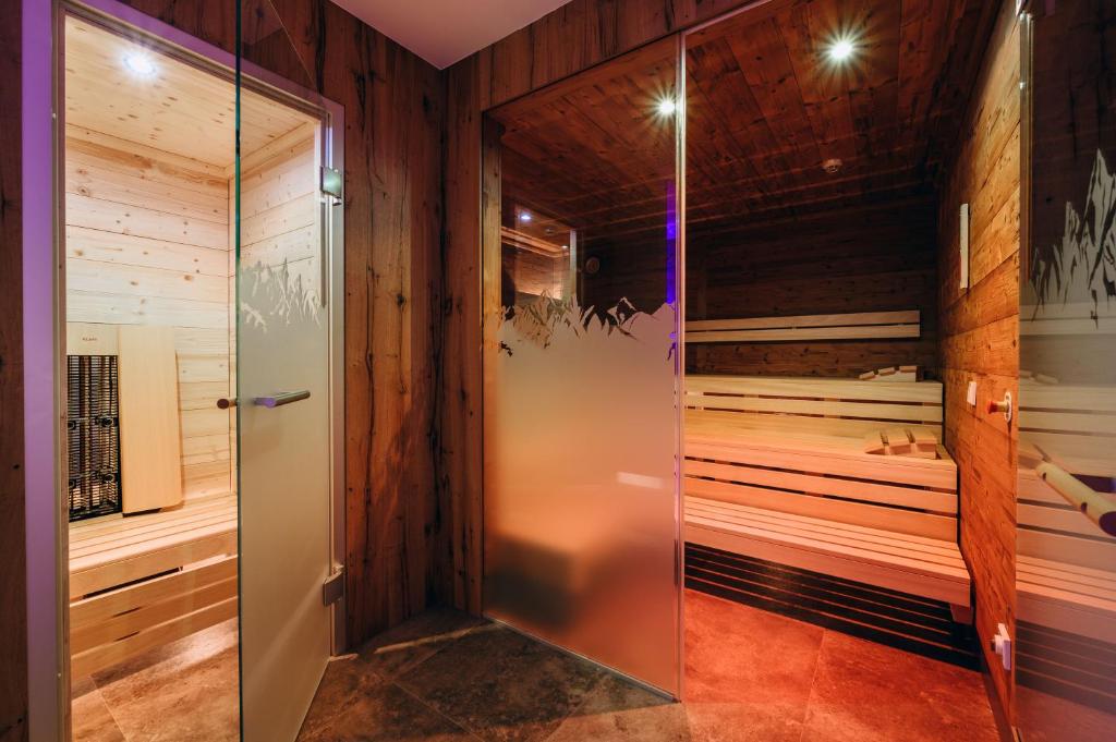 a walk in sauna with wooden walls and a glass door at Hotel Grieserin in Sankt Anton am Arlberg