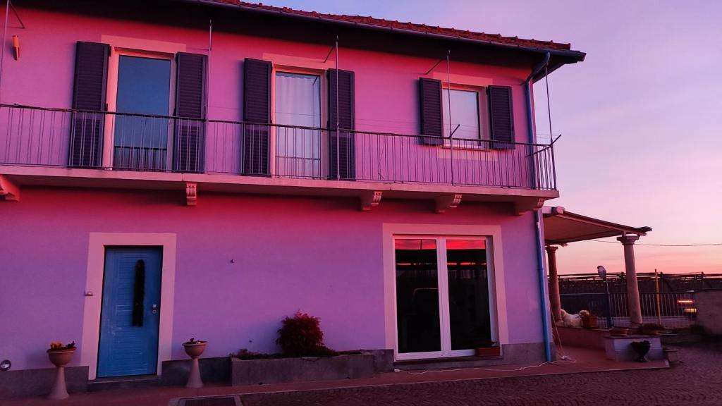 ein rosafarbenes Haus mit blauer Tür und Balkon in der Unterkunft B&B Casa Lilla in Verzuolo