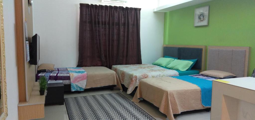 een kamer met drie bedden in een kamer met groen bij NH Studio Apartment Homestay in Wakaf Che Yeh