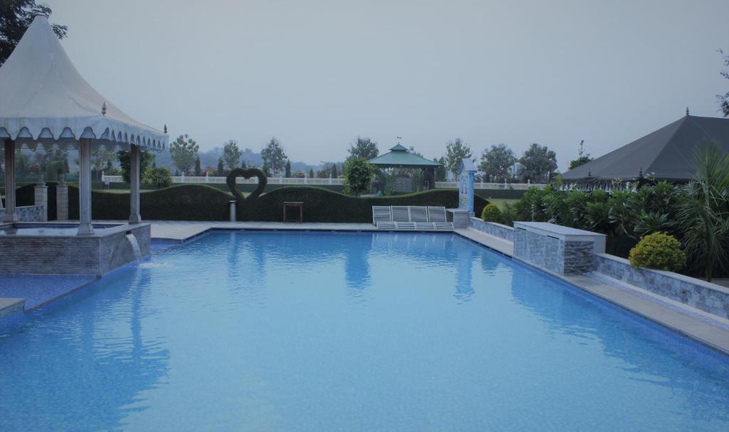 a large blue swimming pool with a gazebo at Amrit Van Resort in Jaipur