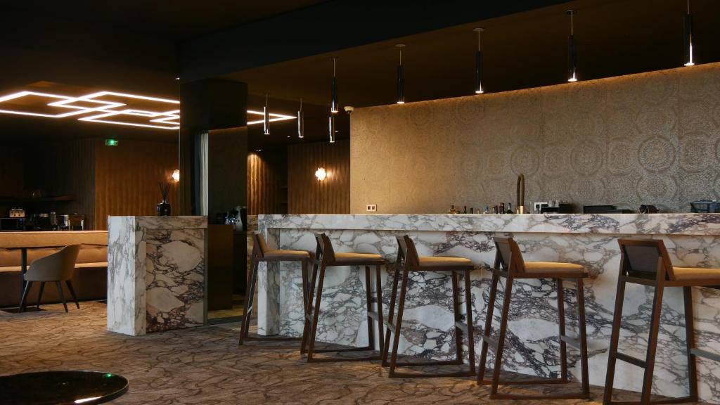 een bar in een restaurant met krukken aan een bar bij Howard Hotel Paris Orly Airport in Paray-Vieille-Poste