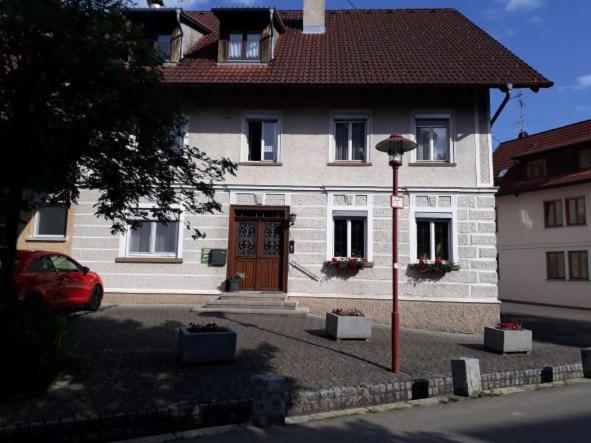 een wit huis met een bruine deur en een rode auto bij Ferien- und Obsthof Dillmann in Langenargen