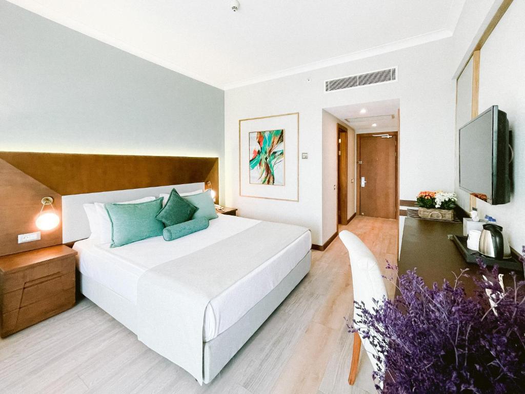 a bedroom with a large white bed with blue pillows at Ilica Hotel Spa & Wellness Resort in Çeşme