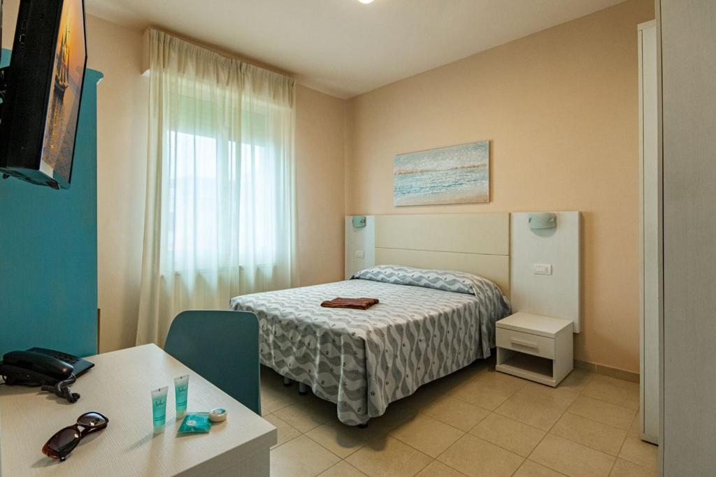 ein kleines Schlafzimmer mit einem Bett, einem Tisch und einem Fenster in der Unterkunft Hotel Villa San Giuseppe in San Bartolomeo al Mare