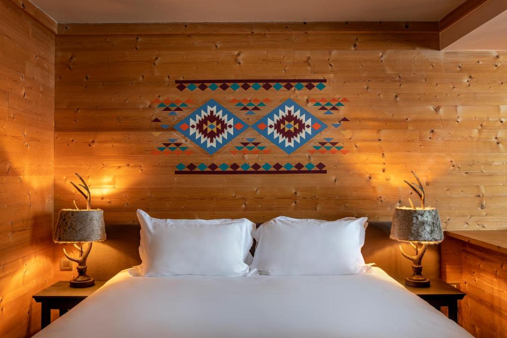 a bedroom with a white bed with two lamps at Chalet Hotel Kaya in Les Menuires