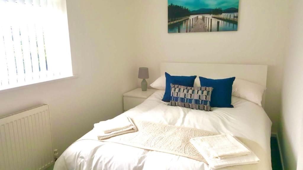 a small bedroom with a white bed with blue pillows at Property Hunter 23 in Darlington