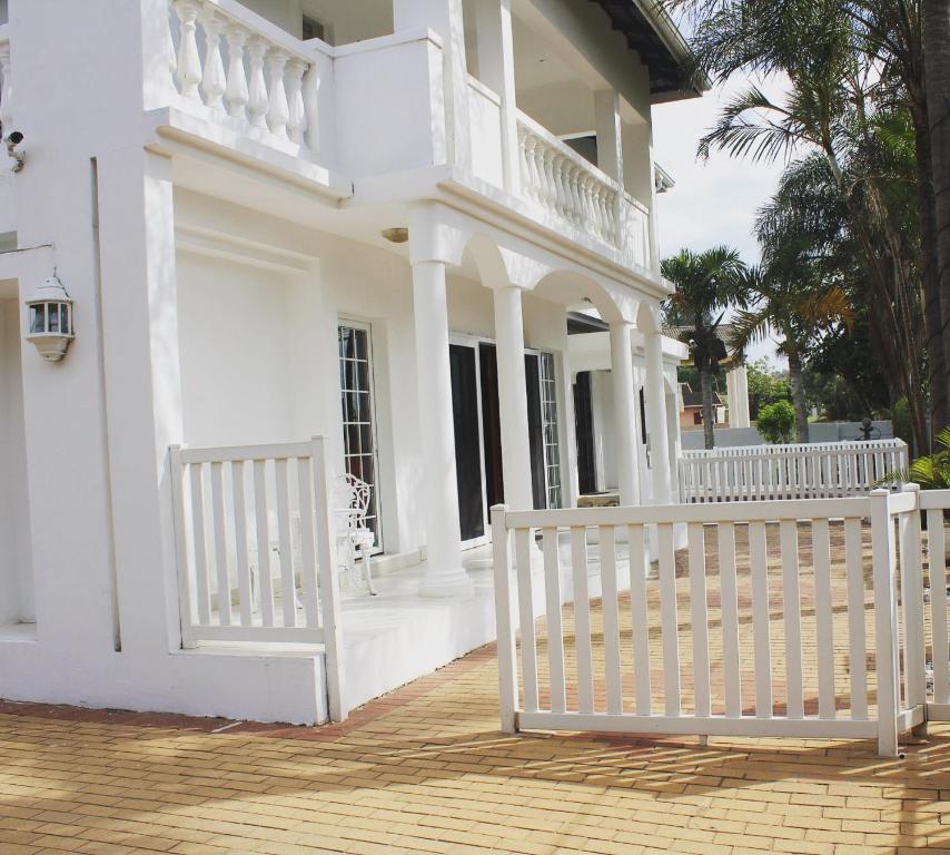 een wit huis met een wit hek ervoor bij The Rose on Fairway in Durban
