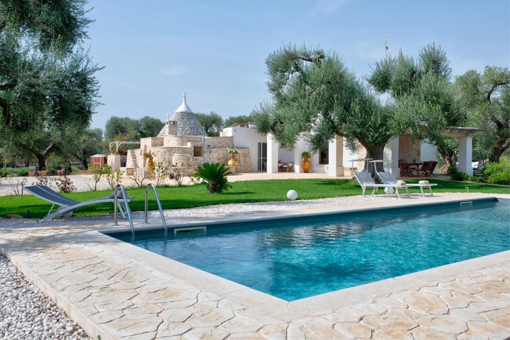 una piscina in un cortile con una casa di Trullo Sunrise - trullo con piscina Privata a San Vito dei Normanni