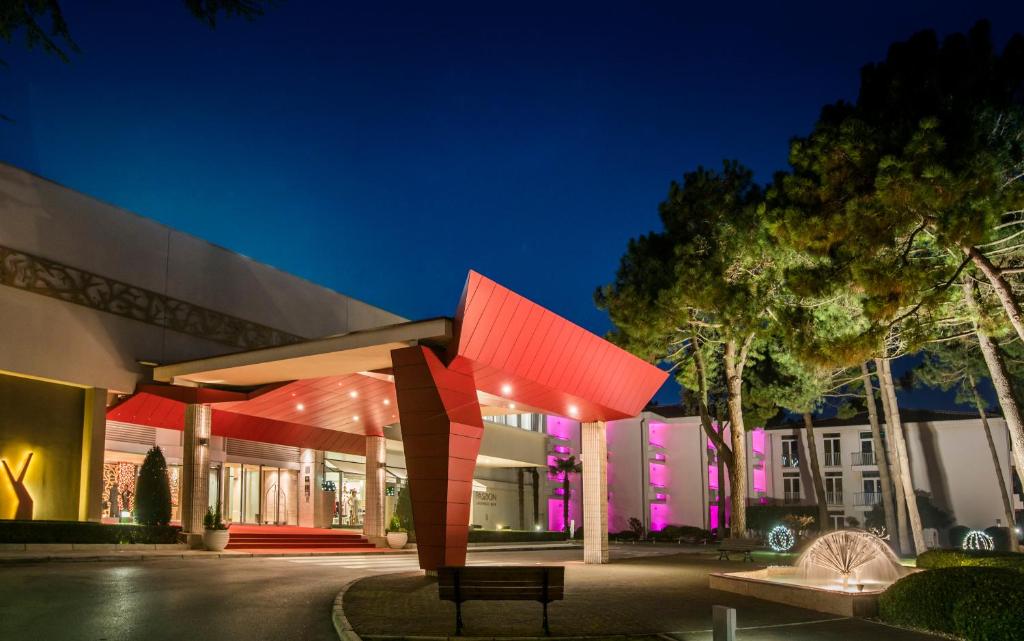 a building with a bench in front of it at night at Hotel Coral Plava Laguna in Umag