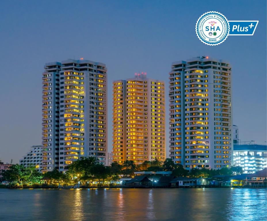 dois edifícios altos ao lado de uma massa de água em Riverine Place Hotel and Residence em Nonthaburi