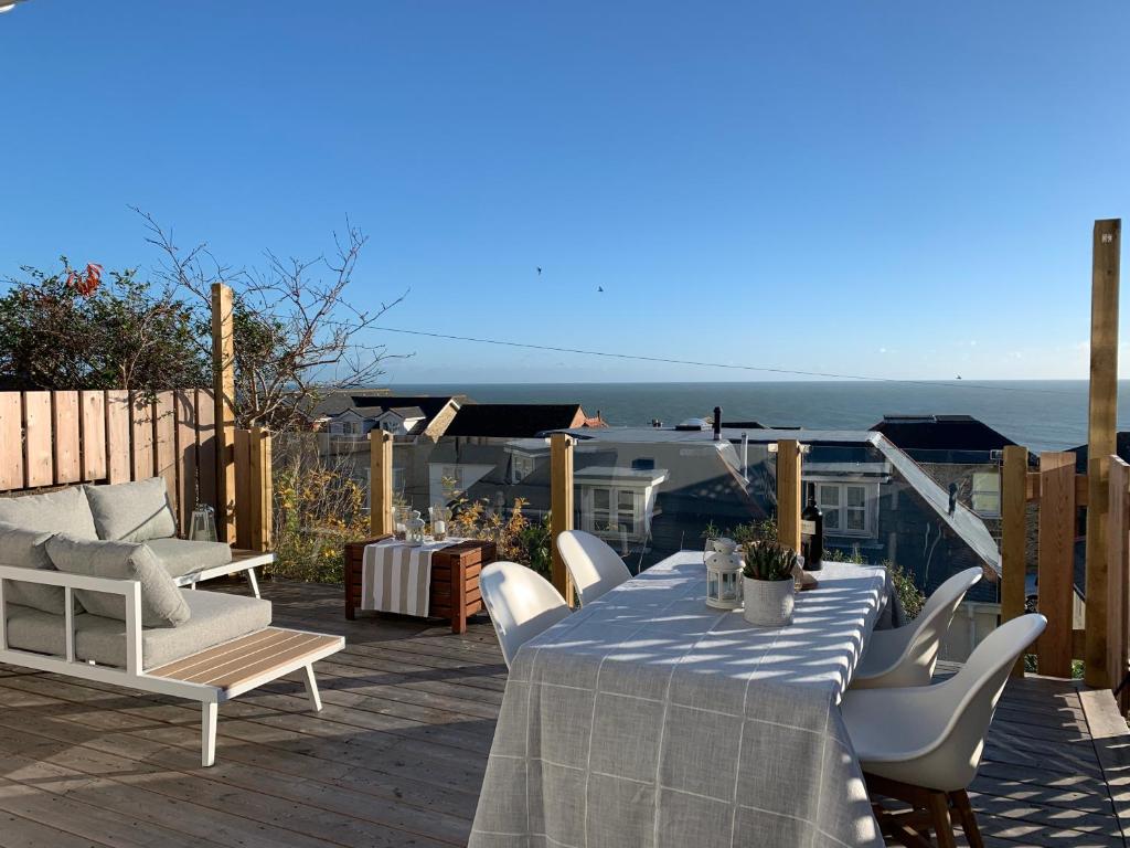 einen Tisch und Stühle auf einer Terrasse mit Meerblick in der Unterkunft 28 North, Stunning Costal home with Generous Ferry Reduction in Ventnor