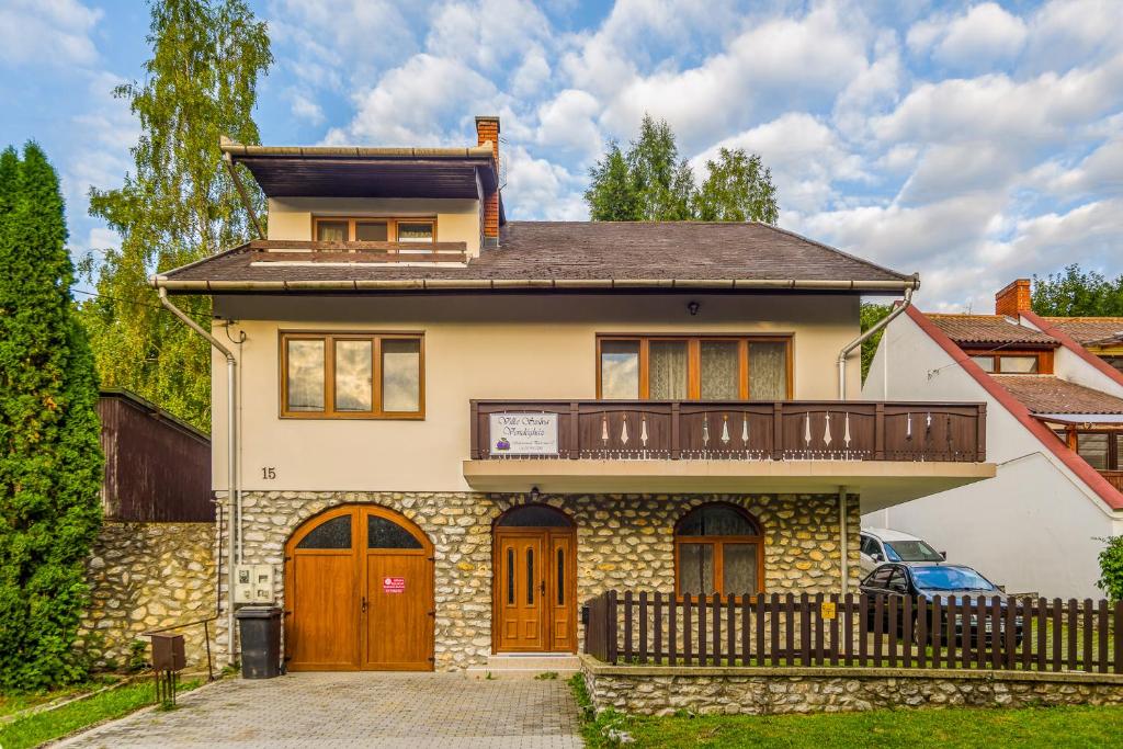 a house with a balcony on top of it at Villa Szilva Vendégház in Szilvásvárad