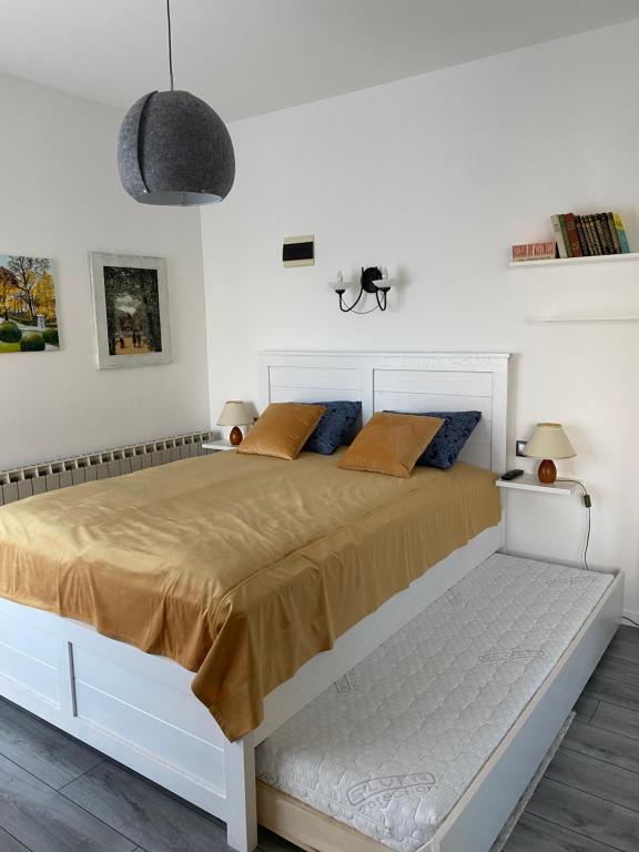 Studio Apartman Lora في Lipik: غرفة نوم بيضاء مع سرير كبير مع وسائد برتقالية