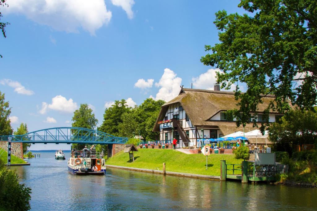 un puente sobre un río con una casa y un barco en Pension und Schänke Lenzer Krug, en Lenz