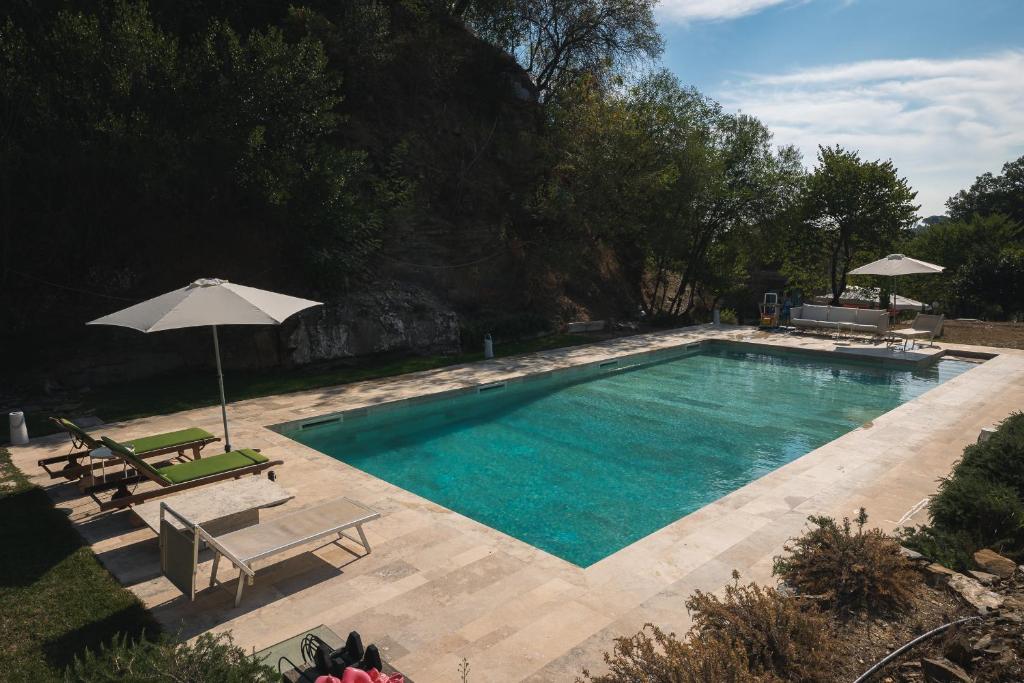 a swimming pool with two chairs and an umbrella at Villa Pietra Viva in Lucignano