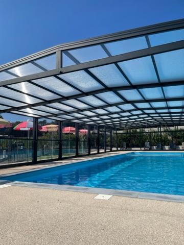 une grande piscine avec un toit en verre dans l'établissement Camping Le Ruisseau, à Saint-André-de-Seignanx