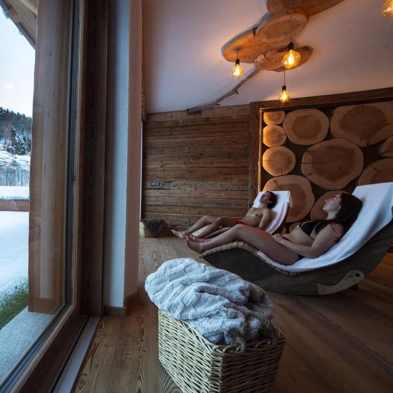 two women laying in hammocks in a room with a window at Hotel Edelweiss in Limone Piemonte