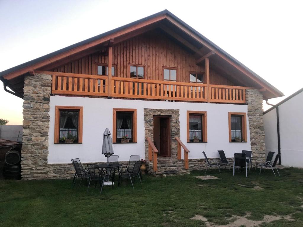 a house with a wooden roof and tables and chairs at Apartmány Diana in Lužice